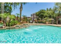 Community pool with lush landscaping and fountain features surrounded by mature trees on a clear, sunny day at 5345 E Van Buren St # 209, Phoenix, AZ 85008