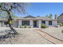 Charming single-story home with a well-manicured front yard, desert landscaping, and mature tree at 6214 W Sunnyside Dr, Glendale, AZ 85304