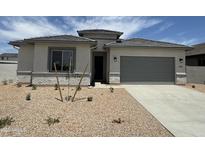 Charming single-story home with a gray garage door, desert landscaping, and a tiled roof at 6952 E Brushy Bill Rd, San Tan Valley, AZ 85143
