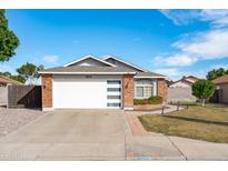 Charming single-story home with a well-maintained lawn, brick accents, and a modern garage door at 8828 E Des Moines St, Mesa, AZ 85207