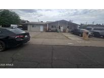 Modest single-story duplex with neutral paint, gravel yard, and American flag accents at 6010 W Coolidge St, Phoenix, AZ 85033
