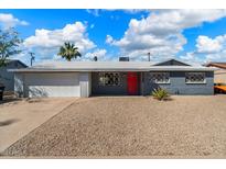 Charming single-story home with a gray exterior, red door, and well-maintained desert landscaping at 7326 E Portland St, Scottsdale, AZ 85257