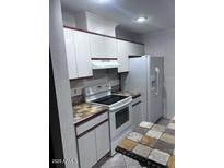 Galley kitchen featuring white cabinetry, black and brown countertops, and white appliances at 8055 E Thomas Rd # H103, Scottsdale, AZ 85251
