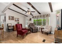 Cozy living room with wood floors, ceiling fan, beamed ceiling and comfortable seating at 8330 E Pueblo Ave, Mesa, AZ 85208