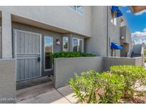 Inviting condo featuring a secure gate, a vibrant garden, and lovely blue awnings over the windows at 220 N 22Nd Pl # 1022, Mesa, AZ 85213