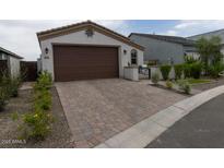 Charming single-Gathering home showcasing a brown garage door and brick paver driveway, surrounded by well-maintained landscaping at 5633 N 206Th Ave, Buckeye, AZ 85396
