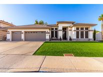 Beautiful single-story home with a manicured lawn, three-car garage, and neutral color palette at 6518 W Louise Dr, Glendale, AZ 85310