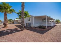 Charming home with a covered porch, desert landscaping, and mature palm trees at 8823 E Billings St, Mesa, AZ 85207