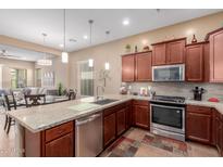 Well-lit kitchen featuring stainless steel appliances, tile flooring and backsplash, granite countertops and pendant lighting at 20556 W Point Ridge Rd, Buckeye, AZ 85396