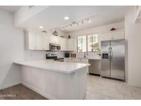 Bright kitchen features stainless steel appliances, white cabinets, subway tile backsplash, and a spacious quartz countertop island at 2315 N 52Nd St # 144, Phoenix, AZ 85008