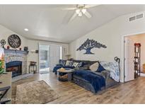 Cozy living room features a stone fireplace, vaulted ceilings, and sliding glass doors to the outdoor patio at 8111 E 5Th Ave, Mesa, AZ 85208