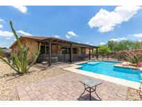 Backyard pool area with desert landscaping, shaded patio, and privacy fence, creating a relaxing outdoor space at 13720 N 148Th Dr, Surprise, AZ 85379
