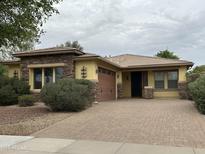 Charming single-story home with a brick driveway, manicured shrubs and stone accents around the windows at 16528 W Lariat Ln, Surprise, AZ 85387