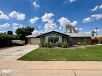 Charming single-story home with a well-manicured lawn and desert landscaping, complemented by a spacious driveway at 8632 E Thornwood Dr, Scottsdale, AZ 85251
