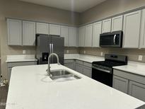 Modern kitchen features stainless steel appliances, gray cabinets, and a white quartz countertop island at 40816 W Sunland Dr, Maricopa, AZ 85138