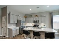 A modern kitchen featuring an island with bar seating, stainless steel appliances, and shaker style cabinets at 40816 W Sunland Dr, Maricopa, AZ 85138