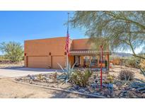 Inviting Southwestern-style home with a desert landscape, an American flag, and a three-car garage at 44421 N 12Th St, New River, AZ 85087