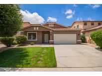 Inviting single-story home showcases a vibrant lawn, desert landscaping, and classic Southwestern architecture with a tile roof at 45309 W Gavilan Dr, Maricopa, AZ 85139