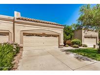 Beige home exterior featuring a garage with beige doors and well-manicured landscaping at 8874 W Piute Ave, Peoria, AZ 85382