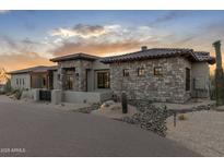 Stunning stone-clad exterior with desert landscaping and a paver driveway, showcasing elegant design and curb appeal at 9456 E Sands Dr, Scottsdale, AZ 85255
