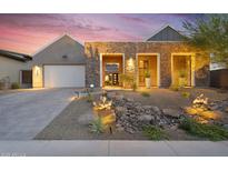Modern home featuring a stone facade, drought-resistant landscaping, and a large garage at sunset at 1337 E Paseo Way, Phoenix, AZ 85042