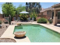 Relaxing backyard pool with lounge chairs, desert landscaping, and striped umbrella at 2894 N Paisley Ave, Casa Grande, AZ 85122