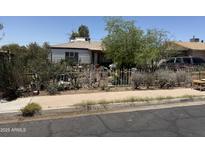 A single-story home features a yard filled with cacti and vegetation behind a wrought iron fence at 2030 N 21St Pl, Phoenix, AZ 85006