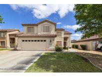 Two-story home with beige stucco, a red tile roof, a two car garage and a well-manicured lawn at 1072 W Windhaven Ave, Gilbert, AZ 85233