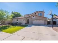 Inviting two-story home featuring a well-manicured lawn, three-car garage, and basketball hoop in the driveway at 1128 E Phelps St, Gilbert, AZ 85295