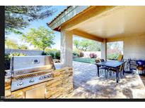 Outdoor kitchen features built-in grill and bar seating in a covered patio area perfect for backyard entertaining at 13280 W Caribbean Ln, Surprise, AZ 85379