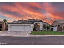 Charming single-story home boasts a well-manicured lawn, three-car garage, and delightful curb appeal under a vibrant, colorful sunset sky at 2982 S Holguin Way, Chandler, AZ 85286