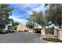 View of the The Village at Stone Creek sign with lush trees and landscaping, with community buildings and parking visible at 4850 E Desert Cove Ave # 241, Scottsdale, AZ 85254