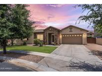 Charming single-story home featuring a stone facade, well-manicured lawn, and a two-car garage at dusk at 6299 S Roanoke St, Gilbert, AZ 85298