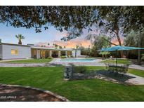 Beautiful backyard featuring a well-maintained lawn, patio, pool, and lounge area, perfect for outdoor enjoyment at 6911 E Thunderbird Rd, Scottsdale, AZ 85254