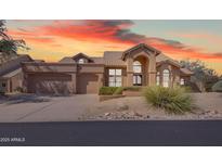 Stunning home with a tan stucco exterior, tile roof, and well-maintained landscaping against a sunset sky at 12605 E Kalil Dr, Scottsdale, AZ 85259