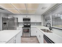 Modern kitchen featuring stainless steel appliances, white cabinets, and a sleek design, perfect for cooking and entertaining at 17201 N 35Th Dr, Glendale, AZ 85308