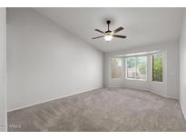 Spacious carpeted bedroom featuring a ceiling fan and natural light from large windows at 19530 N 84Th Ave, Peoria, AZ 85382