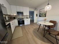 Bright kitchen featuring stainless steel appliances, white cabinets, and a cozy dining area at 434 N 56Th St, Mesa, AZ 85205