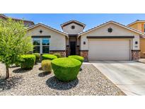 Charming single-story home featuring a well-manicured front yard with decorative stone and vibrant green shrubs at 5519 N 187Th Ln, Litchfield Park, AZ 85340