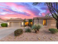 Charming single-story home showcasing a manicured desert landscape and three-car garage, bathed in the warm hues of sunset at 3523 W Buckhorn Trl, Phoenix, AZ 85083