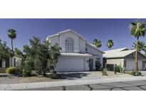 Charming two-story home featuring a white exterior, arched window, and a well-manicured desert landscape at 4530 E Desert Wind Dr, Phoenix, AZ 85044