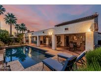 Inviting backyard pool with covered patio, lounge chairs, and lush palm trees in an elegant outdoor setting at 6133 E Saddleback St, Mesa, AZ 85215