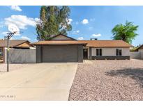 Charming single-story home featuring a gray brick garage and low maintenance rock landscaping at 6751 W Cameron Dr, Peoria, AZ 85345