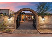 Inviting entrance to a Spanish-style home with a brick archway and charming desert landscaping at 8035 E Paraiso Dr, Scottsdale, AZ 85255
