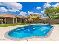Inviting backyard pool with lounge umbrella, lush landscaping, and a beautiful blue sky at 2111 E Yellowstone Pl, Chandler, AZ 85249