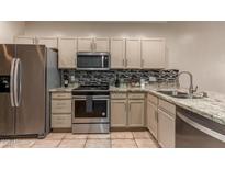 This kitchen features stainless steel appliances, tile backsplash, granite countertops, and light cabinetry at 205 N 74Th St # 166, Mesa, AZ 85207