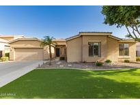 Charming single story home with a two car garage, green grass, desert landscaping, and well kept yard at 2183 W Hawken Way, Chandler, AZ 85286