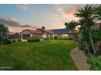 Charming single-story home featuring a lush green lawn, desert landscaping, and solar panels at 5710 E Anderson Dr, Scottsdale, AZ 85254
