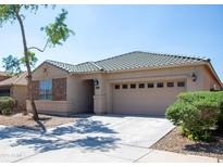 Inviting single-story home featuring a two-car garage, stone accents, and landscaped front yard at 9025 W Crown King Rd, Tolleson, AZ 85353