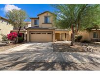 Two-story home with tan stucco, two-car garage, desert landscaping, covered porch and blooming shrub at 973 E Corral St, Avondale, AZ 85323